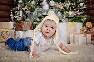 Baby in elf costume playing with old wooden train and soft toy bears under the Christmas tree, vintage.