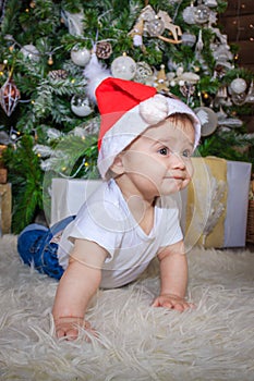 Baby in elf costume playing with old wooden train and soft toy bears under the Christmas tree, vintage.