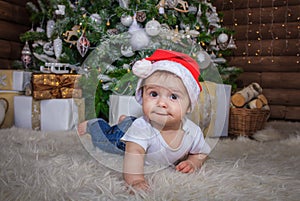 Baby in elf costume playing with old wooden train and soft toy bears under the Christmas tree, vintage.