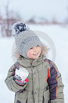 Baby enjoys winter playing snowballs