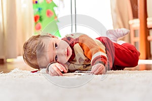 Baby entertains in winter lying on the carpet in his living room photo