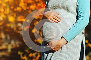 Baby expectation. Pregnant woman outdoors in autumn. Woman having happy pregnancy time