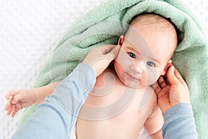 Baby face massage background. Mother gently stroking baby boy face with both hands. Close up cropped shot.