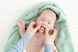 Baby face massage background. Mother gently stroking baby boy face with both hands. Close up cropped shot.