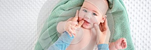 Baby face massage banner with copy space. Mother gently stroking baby boy face with both hands. Close up cropped shot.