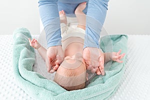 Baby face massage concept. Masseuse or mother gently stroking baby boy face with both hands. Close up cropped shot.