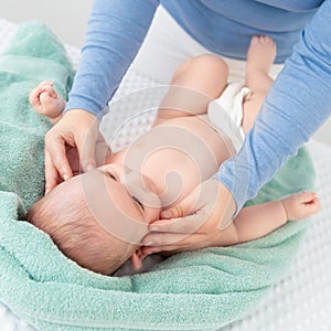 Baby face massage. Mother gently stroking baby boy face with both hands. Close up cropped shot.