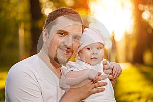 Baby with faher in the park in the rays of sunset. Toddler on the nature outdoors. Backlight. Summertime family scene