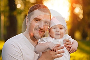 Baby with faher in the park in the rays of sunset. Toddler on the nature outdoors. Backlight. Summertime family scene