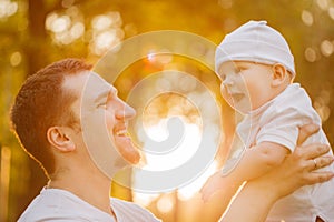 Baby with faher in the park in the rays of sunset. Toddler on the nature outdoors. Backlight. Summertime family scene