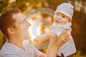 Baby with faher in the park in the rays of sunset. Toddler on the nature outdoors. Backlight. Summertime family scene