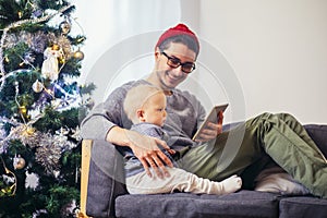 Baby with father sitting and using digital tablet during Christmas