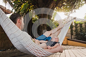 Baby and father are sleeping in a hammock