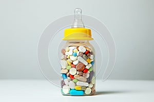 Baby feeding bottle filled with pills. With mother`s milk, the child gets everything the mother eats. closeup.