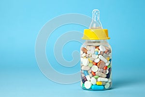 Baby feeding bottle filled with pills. With mother`s milk, the child gets everything the mother eats. Copy space for text