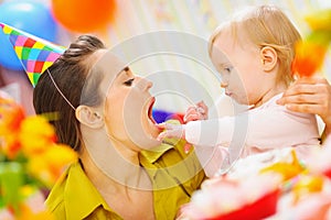 Baby feeding mother with birthday cake