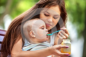 Baby feeding spoon by mother in park outdoor. Weaning .