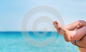 Baby feet on the background of the sea. Selective focus.