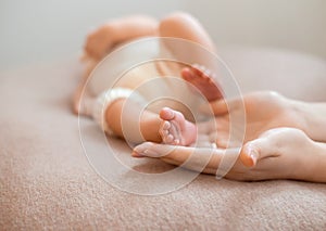 Baby feet cupped into mothers hands. Gentle blurred background of the feet and heels of a newborn