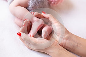 Baby feet cupped into mothers hands. Gentle blurred background of the feet and heels of a newborn