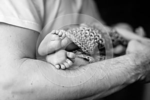Baby feet in father hands. Black-and-white photo. Baby's feet in