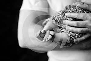 Baby feet in father hands. Black-and-white photo. Baby's feet in