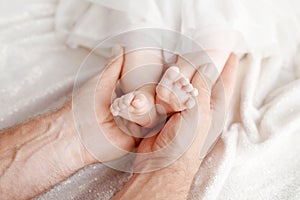 Baby feet in father hands. Tiny newborn baby`s feet on male hand