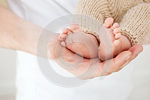 Baby feet in father hands. Tiny Newborn Baby`s feet on male hands closeup. Dad and his child. Happy Family concept