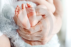 Baby feet in father hands. Tiny newborn baby`s feet on male hands closeup. Dad and his child. Happy Family concept. Beautiful