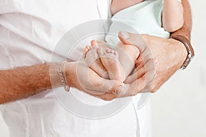 Baby feet in father hands. Tiny newborn baby`s feet on male hands closeup. Dad and his child. Happy Family concept. Beautiful