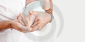 Baby feet in father hands. Tiny newborn baby`s feet on male hands closeup. Dad and his child. Happy Family concept. Beautiful