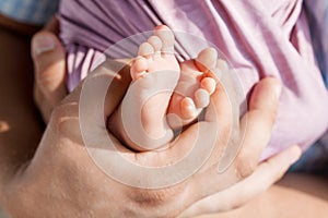 Baby feet in father hands. Tiny newborn baby`s feet on male hands closeup. Dad and his child. Happy Family concept. Beautiful