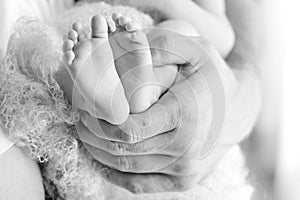 Baby feet in father hands. Tiny newborn baby`s feet on male hands closeup. Dad and his child. Happy Family concept. Beautiful