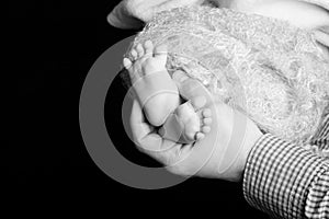 Baby feet in father hands. Tiny Newborn Baby`s feet on male hands closeup. Dad and his child. Happy Family concept. Beautiful