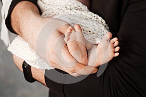 Baby feet in father hands. Tiny Newborn Baby`s feet on male Shaped hands closeup. Dad and his Child. Happy Family concept.