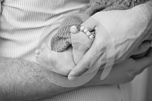 Baby feet in father hands. Tiny Newborn Baby`s feet on male shaped hands closeup. Dad and his Child. Happy Family concept