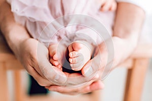 Baby feet in the hands of the father. Tiny legs of a newborn baby on male hands, close-up