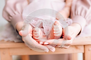 Baby feet in the hands of the father. Tiny legs of a newborn baby on male hands, close-up