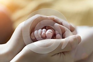 Baby feet. Mom holds with tenderness and love in his hands the small legs of a newborn. New life, parental protection