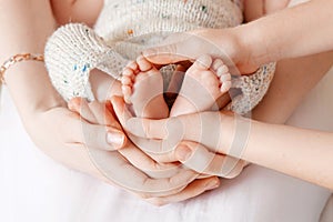 Baby feet in mother and brother hands. Tiny Newborn Baby`s feet closeup. Mom and her Childs. Happy Family concept. Beautiful