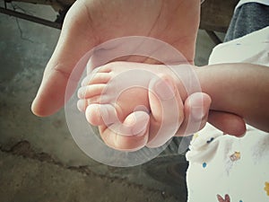 baby feet in mother hands close up with soft focus and vintage tone