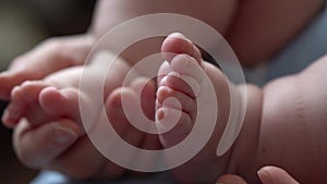 Baby Feet On Mother Hands. Cute Tiny Newborn Kid's Legs On Female Embrace Closeup. Mom And Her Child. Happy Family
