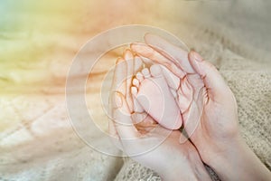 Baby feet in mother hands. Mom and her Child. Happy Family concept. Beautiful conceptual image of Maternity