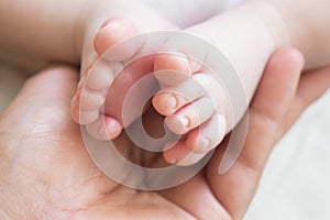 Father holds the leg of a newborn baby boy