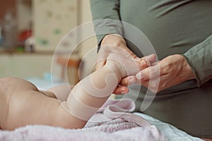 Baby feet in mother hands. Mom and her Child. Masseur massaging little baby`s foot. Happy Family concept.