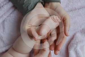 Baby feet in mother hands. Mom and her Child. Masseur massaging little baby`s foot. Happy Family concept.