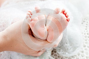 Baby feet in mother hands. Tiny newborn baby`s feet on female shaped hands closeup. Mom and her child