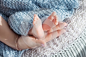 Baby feet in mother hands. Tiny newborn baby`s feet on female shaped hands closeup. Mom and her child. Beautiful conceptual image