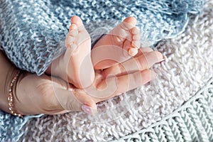 Baby feet in mother hands. Tiny newborn baby`s feet on female shaped hands closeup. Mom and her child. Beautiful conceptual image