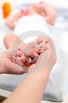 Baby feet in mother hands. Tiny Newborn Baby`s feet on female Shaped hands closeup. Mom and her Child. Happy Family